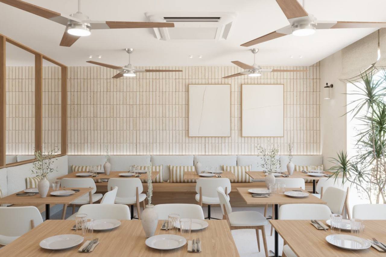 Salón con mesas de madera, bancos y tonos blancos y arena